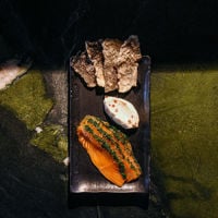 An artfully presented plate of salmon sits on top of a green marble counter at Aurora.