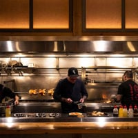 The open kitchen sees one chef plating while the other cooks over the open flame at Shobosho.