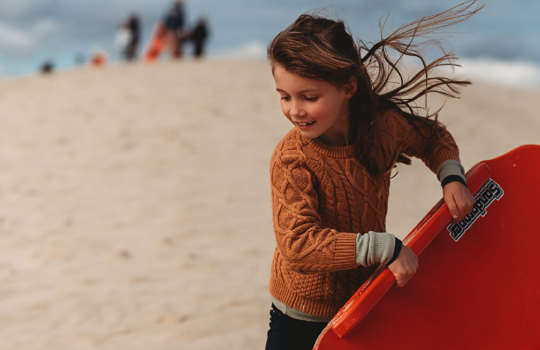 young girl sandboarding at Little Sahara